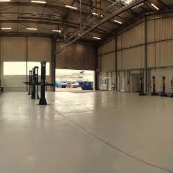 Spacious and clean industrial warehouse interior with forklifts and large open entrance.